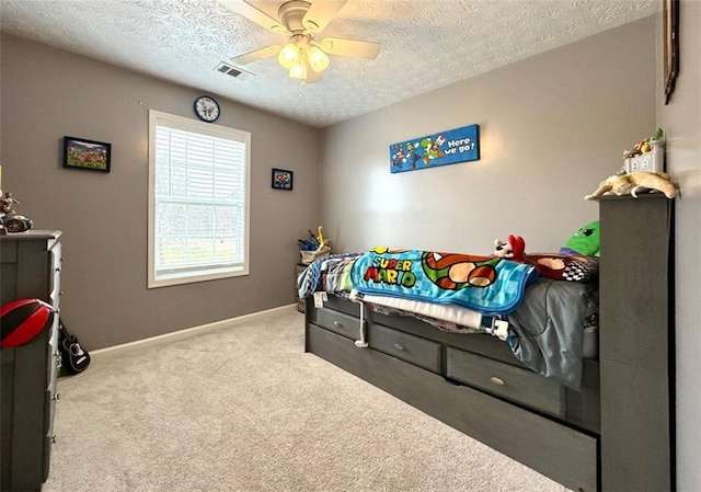 carpeted bedroom featuring a textured ceiling, baseboards, a ceiling fan, and visible vents