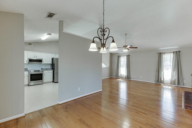 41 Pebble Ct, Hoschton, GA 30548 - interior space with visible vents, light wood-style flooring, baseboards, ceiling fan with notable chandelier, and vaulted ceiling