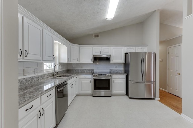 41 Pebble Ct, Hoschton, GA 30548 - kitchen with white cabinetry, lofted ceiling, a sink, and stainless steel appliances
