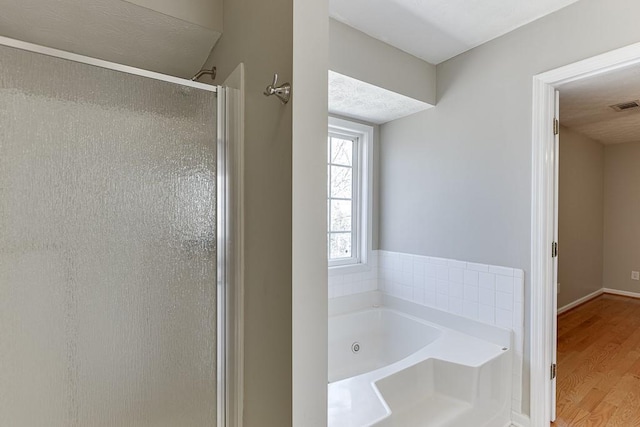 41 Pebble Ct, Hoschton, GA 30548 - bathroom with a stall shower, a tub with jets, wood finished floors, a textured ceiling, and visible vents