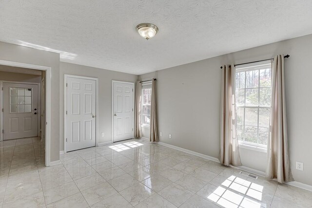 41 Pebble Ct, Hoschton, GA 30548 - unfurnished bedroom with a textured ceiling, visible vents, and multiple windows