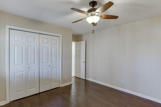41 Pebble Ct, Hoschton, GA 30548 - unfurnished bedroom featuring dark wood-type flooring, baseboards, a closet, and a ceiling fan