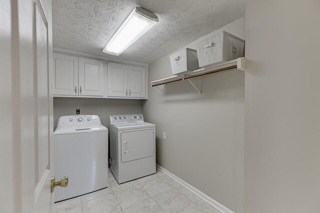 41 Pebble Ct, Hoschton, GA 30548 - clothes washing area with a textured ceiling, marble finish floor, baseboards, washer and dryer, and cabinet space