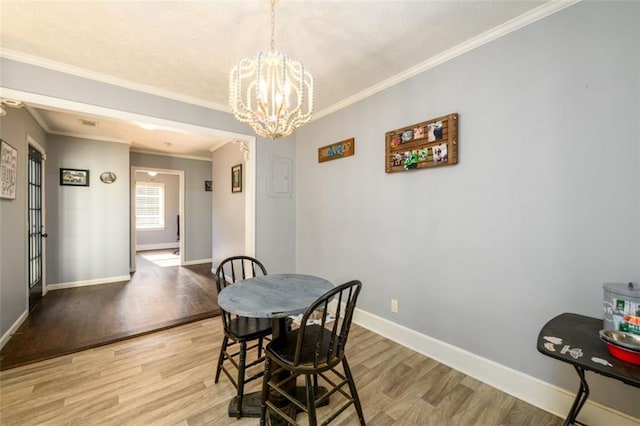 dining room featuring crown molding, light hardwood / wood-style floors, and a chandelier