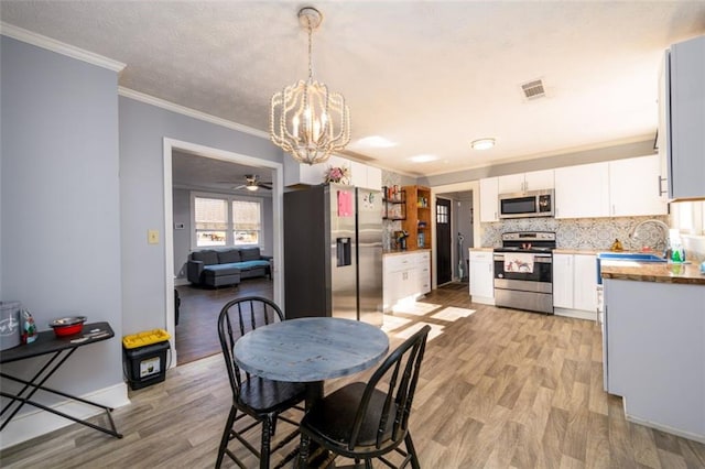 dining area featuring ornamental molding, light hardwood / wood-style floors, and ceiling fan with notable chandelier