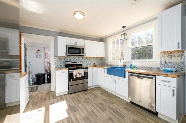 kitchen with hanging light fixtures, sink, stainless steel appliances, and white cabinets