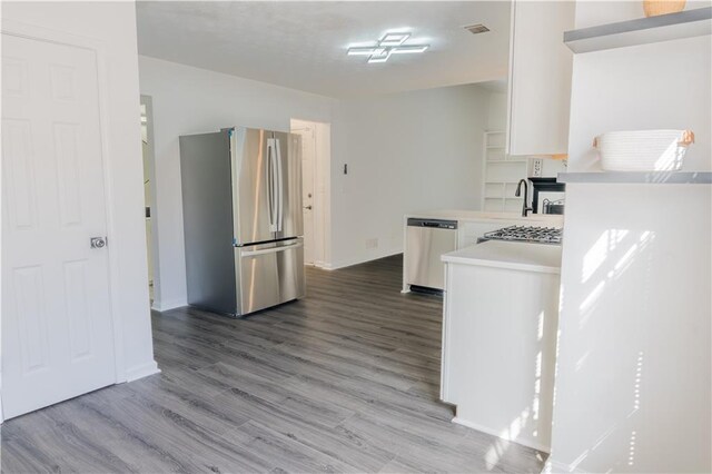 kitchen with stainless steel appliances, white cabinetry, vaulted ceiling, and plenty of natural light