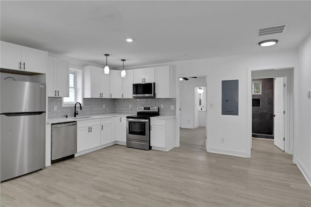 kitchen featuring sink, white cabinetry, hanging light fixtures, stainless steel appliances, and light hardwood / wood-style floors