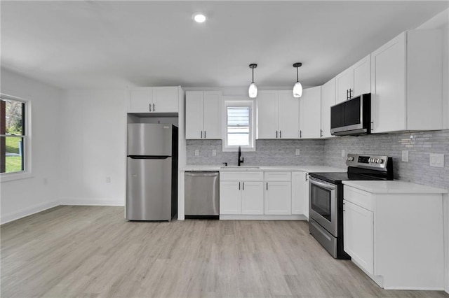 kitchen with sink, white cabinetry, appliances with stainless steel finishes, pendant lighting, and decorative backsplash