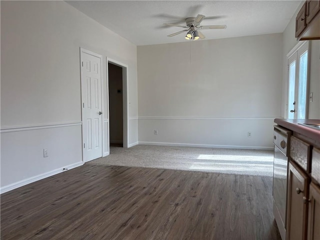 unfurnished room with dark wood-type flooring, ceiling fan, and baseboards