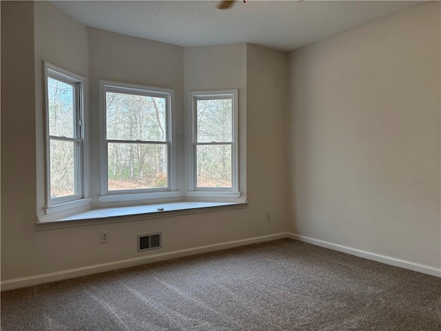 empty room with baseboards, visible vents, and carpet flooring