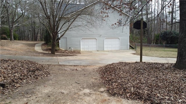 view of side of home featuring driveway, a garage, and fence