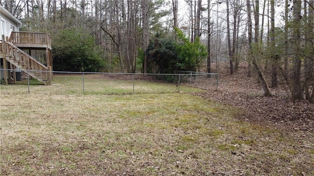 view of yard with fence, a wooden deck, and stairs