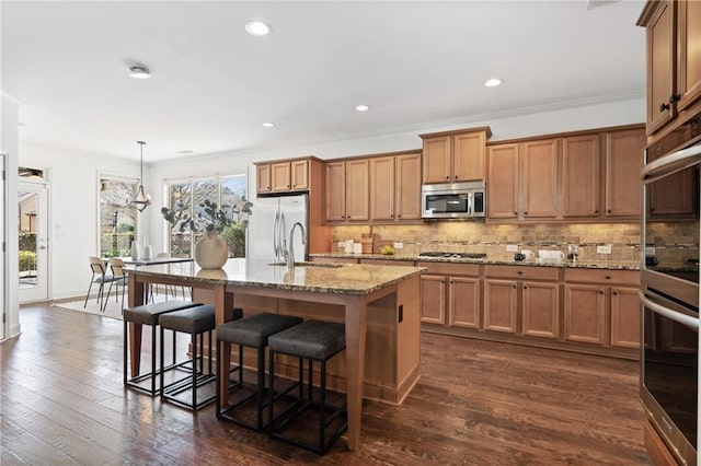 kitchen featuring brown cabinetry, tasteful backsplash, appliances with stainless steel finishes, and a sink