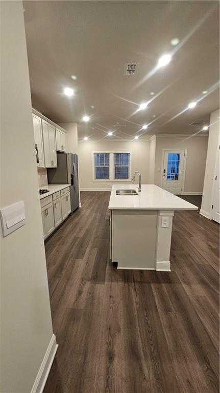 kitchen with sink, dark hardwood / wood-style flooring, white cabinetry, and a kitchen island with sink