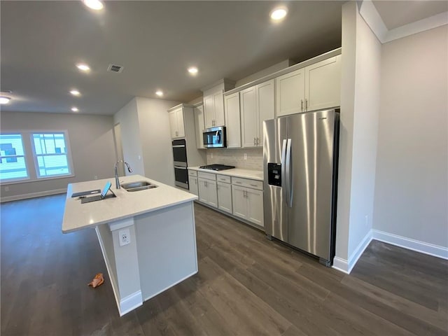 kitchen with sink, white cabinets, an island with sink, backsplash, and appliances with stainless steel finishes