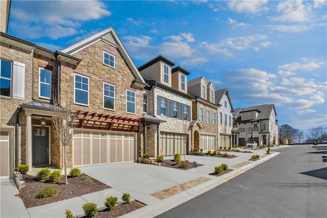 view of front of home with a garage, driveway, stone siding, and a residential view