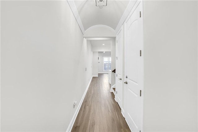 hall with ornamental molding, wood finished floors, and baseboards