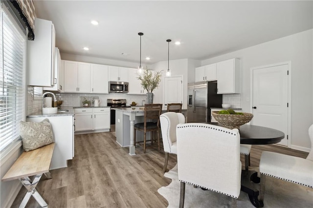 kitchen with a center island, sink, hanging light fixtures, stainless steel appliances, and white cabinets