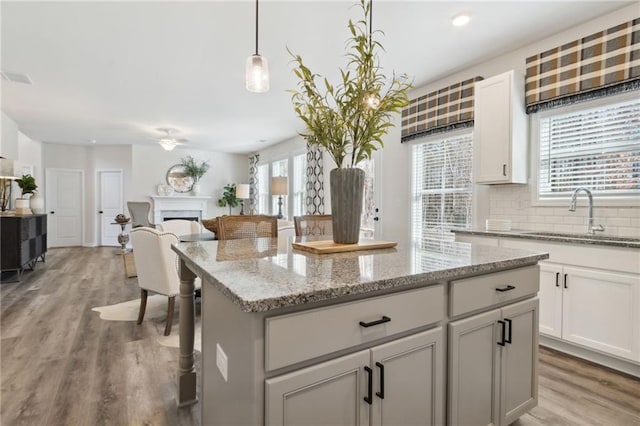 kitchen featuring a center island, sink, hanging light fixtures, and light hardwood / wood-style flooring