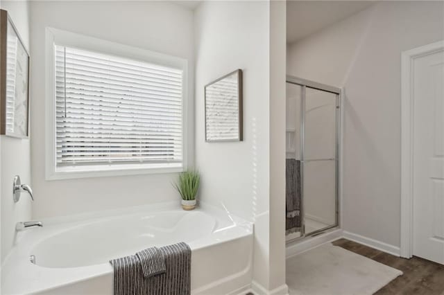 bathroom with plus walk in shower, wood-type flooring, and a wealth of natural light