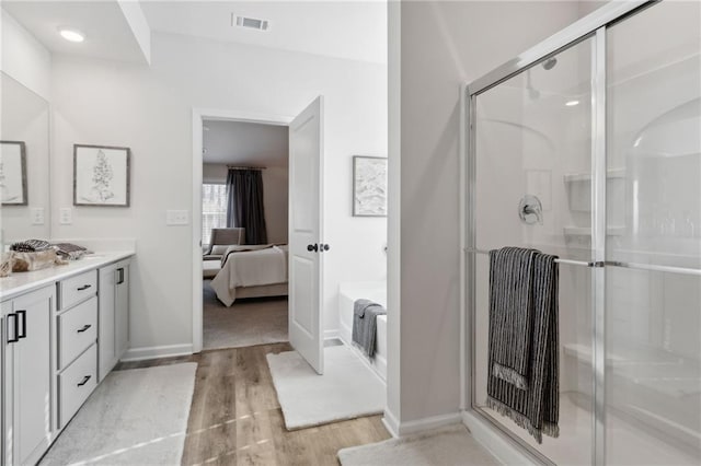 bathroom with hardwood / wood-style floors, vanity, and a shower with door