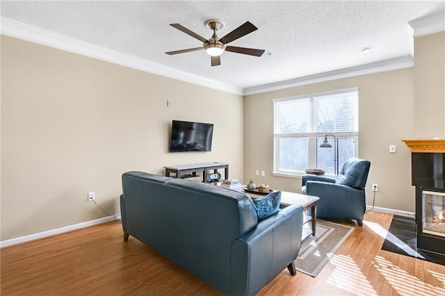 living room featuring a tile fireplace, hardwood / wood-style flooring, ceiling fan, and ornamental molding