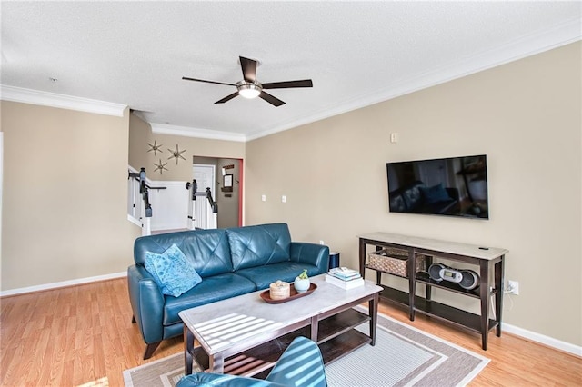 living room with a textured ceiling, ceiling fan, light wood-type flooring, and ornamental molding