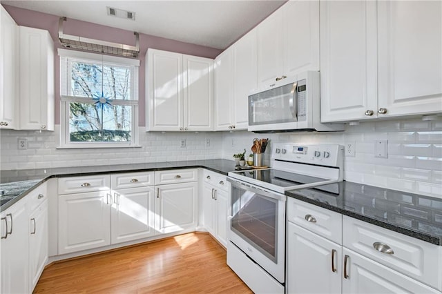 kitchen with decorative backsplash, white appliances, and white cabinetry