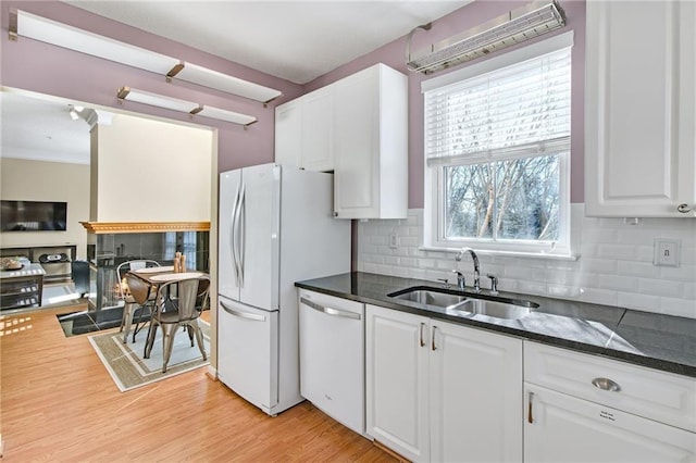 kitchen with white cabinetry, sink, backsplash, light hardwood / wood-style floors, and white appliances