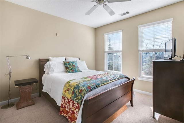 bedroom with ceiling fan, light carpet, and multiple windows