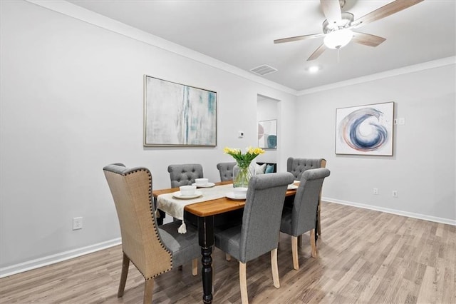 dining area featuring ornamental molding, light wood-type flooring, visible vents, and baseboards