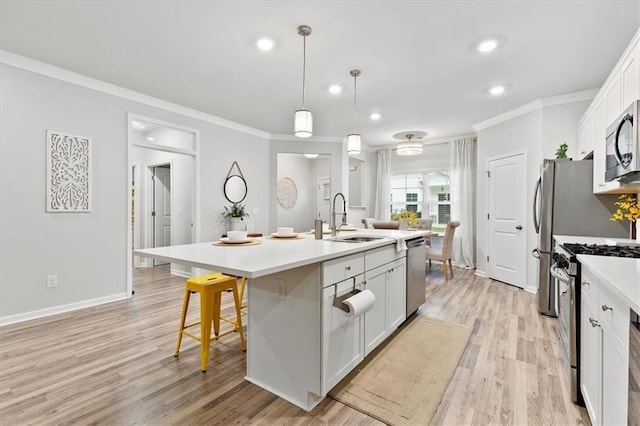 kitchen featuring an island with sink, a kitchen breakfast bar, stainless steel appliances, white cabinetry, and a sink