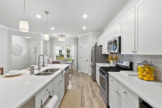 kitchen with appliances with stainless steel finishes, light countertops, a sink, and crown molding