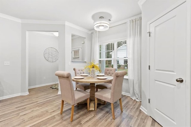 dining room with baseboards, light wood finished floors, and crown molding