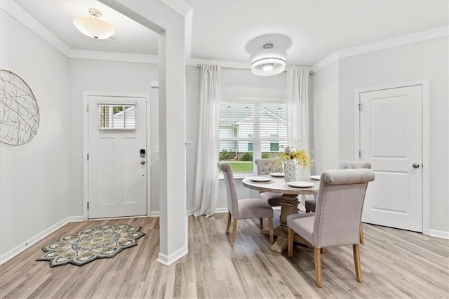 dining space featuring baseboards, light wood finished floors, and crown molding