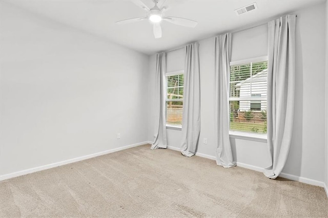 carpeted empty room featuring ceiling fan, plenty of natural light, visible vents, and baseboards