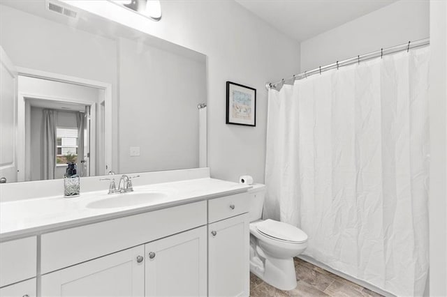 bathroom with toilet, curtained shower, vanity, and visible vents