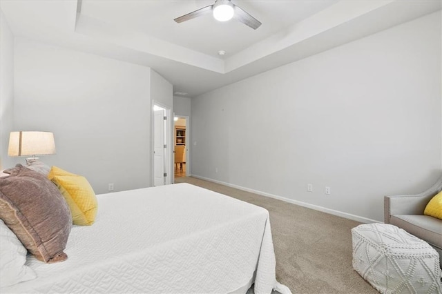 bedroom with carpet, a tray ceiling, ceiling fan, and baseboards