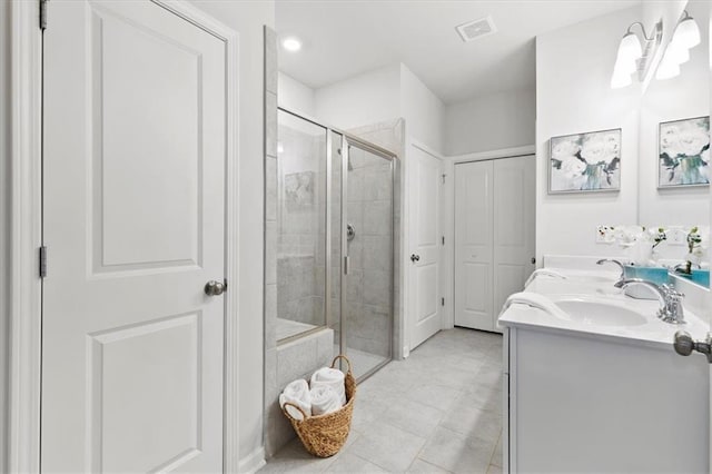 bathroom with double vanity, a shower stall, visible vents, and a sink