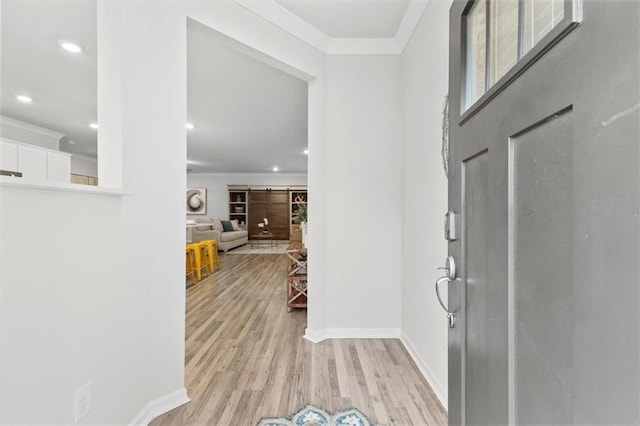 entrance foyer featuring crown molding, light wood finished floors, recessed lighting, a barn door, and baseboards