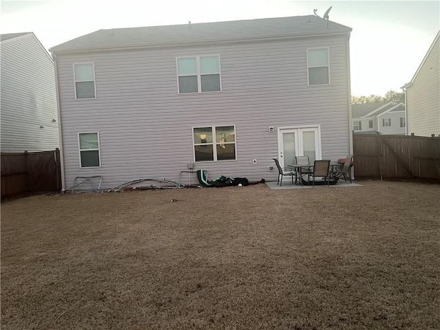 back of property with a yard, a patio area, and french doors