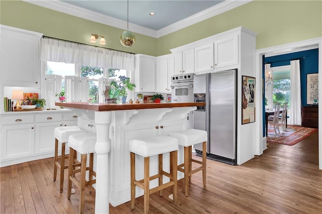 kitchen with stainless steel appliances, white cabinets, a kitchen breakfast bar, and light hardwood / wood-style flooring