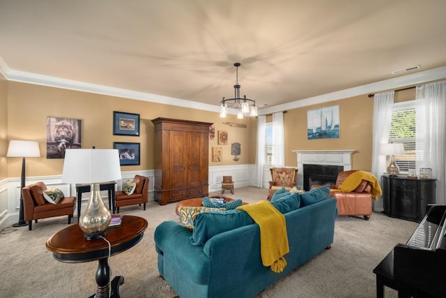 living area with light carpet, a wainscoted wall, visible vents, a glass covered fireplace, and crown molding