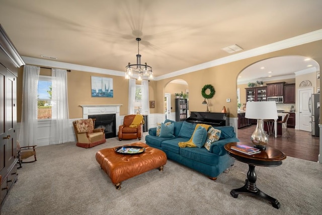 living room featuring arched walkways, carpet floors, wainscoting, and a glass covered fireplace