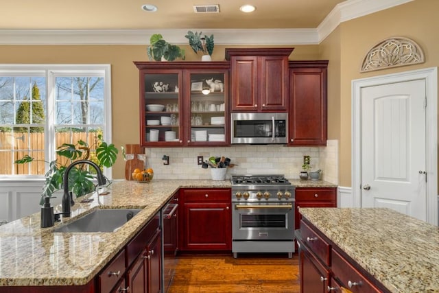 kitchen with stainless steel appliances, reddish brown cabinets, and a sink