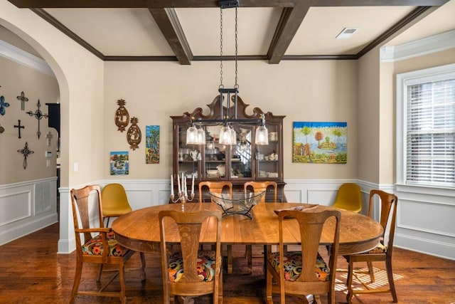 dining room featuring arched walkways, wainscoting, wood finished floors, and beam ceiling