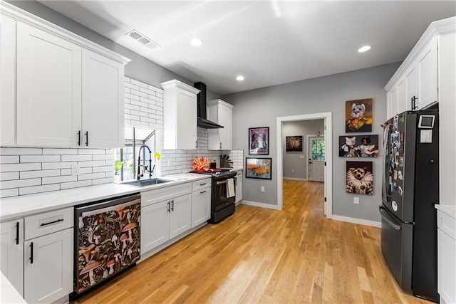 611 Pickett St SE, Atlanta, GA 30316 - kitchen with black appliances, a sink, wall chimney exhaust hood, decorative backsplash, and white cabinetry