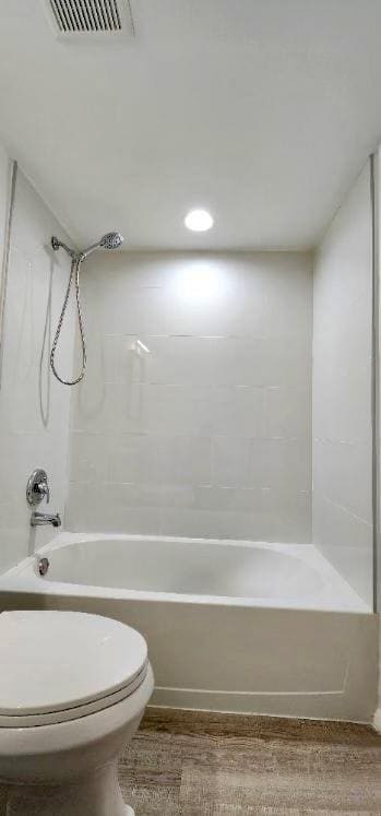 bathroom with wood-type flooring, bathtub / shower combination, and toilet