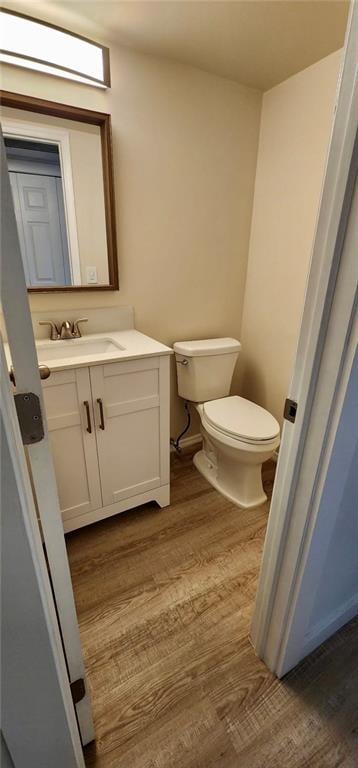 bathroom with hardwood / wood-style floors, toilet, and vanity